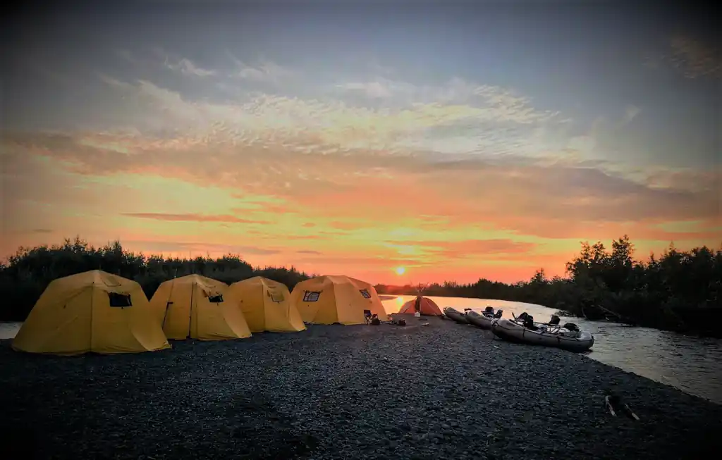 Wilderness camp at evening on an Alaska river, waders drying by the fire